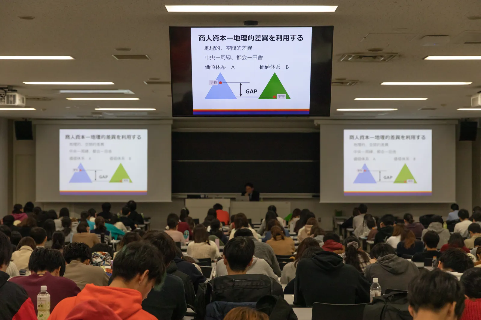 東洋大学の大教室。前方のスクリーンに講義のスライド、手前に多くの学生